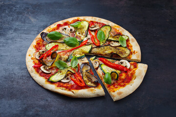 Traditionelle italienische Veggie Pizza mit Aubergine, Pilzen und Zucchini serviert als close-up auf einem alten rustikalen Board mit Textfreiraum 