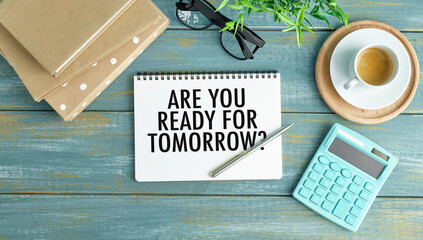 Are you ready for tomorrow? words on notebook with calculator and cup coffee on wooden background.