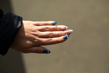 Beautiful nails of girl. Manicure on fingers. Blue nails with pebbles.