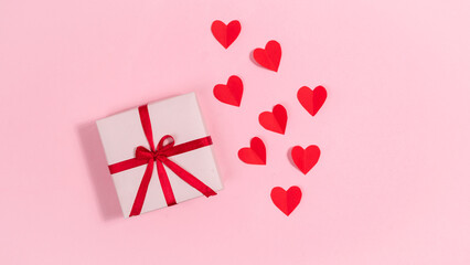 Red hearts, symbols of love near gift box tied with a red ribbon. Greeting card. Valentine's day holiday.
