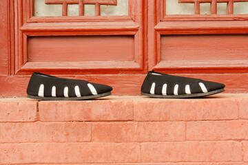 a pair of monk's shoes in front of a red wall and red windows