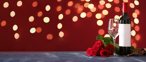 Bottle of wine, red rose flowers, glass and corkscrew on table against blurred lights. Valentine's Day celebration