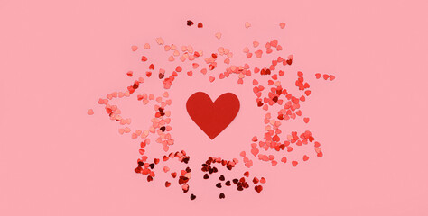 Composition with red paper heart and confetti on pink background. Valentines Day celebration