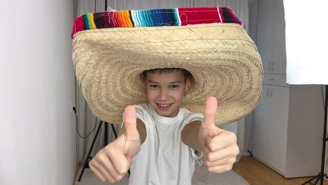 boy in a huge mexican hat shows thumbs up on both hands class he approves something place for text on a white background Young Mexican patriot with a ranger hat celebrating El Grito de Independencia