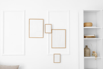 Shelving unit and blank photo frames hanging on light wall