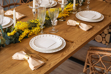 Beautiful table setting with mimosa flowers and candles in room
