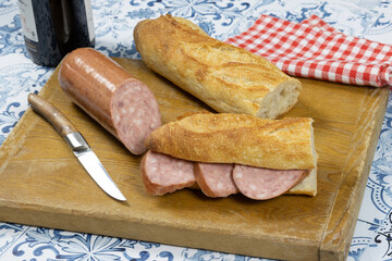 saucisson à l'ail et baguette de pain sur un planche à découper