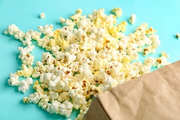 Paper bag with tasty popcorn on color background, closeup