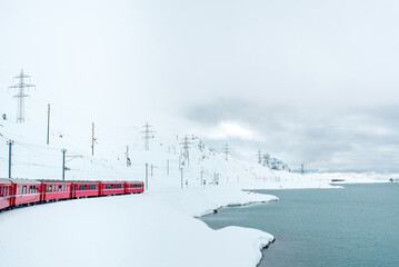 Tourist red Swiss train rides through the snowy Alps. Winter at the ski resort
