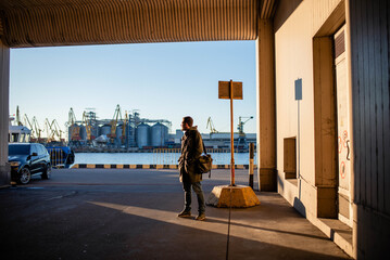 Male businessman stands in the seaport on a sunny day
