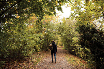 Obraz premium A man traveler walks through the woods. Beautiful wild nature landscape in forest. Hiking journey on tourist trail. Outdoor adventure. Travel and exploration. Healthy lifestyle, leisure activities