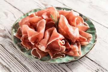 Plate with slices of delicious ham on light wooden background