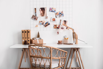 Workplace with Christmas gift, cup and folders near light wall