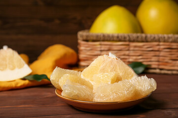 Plate with slices of sweet pomelo fruit on wooden table, closeup