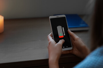 Young woman with discharged mobile phone at home during blackout, closeup