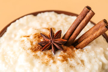 Bowl with delicious rice pudding, anise and cinnamon on beige background, closeup