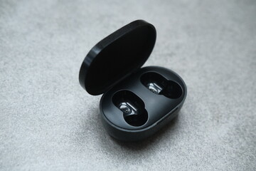 Black bluetooth headphones and case for charge. Listening to the music