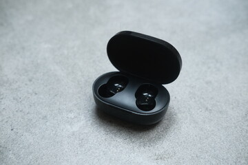 Black bluetooth headphones and case for charge. Listening to the music