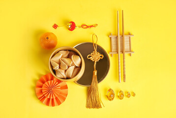 Bowl of fortune cookies, mandarin and Chinese symbols on yellow background