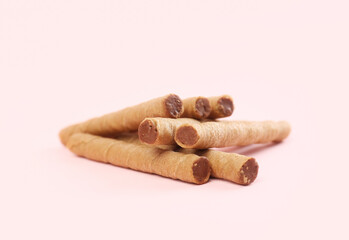 Tasty wafer rolls with boiled condensed milk on pink background