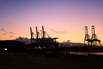 Fototapeta na wymiar silhouette of the industrial port of malaga at sunset with seagulls flying overhead