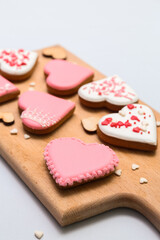 Obraz na płótnie Canvas Wooden board with tasty heart shaped cookies on light background, closeup. Valentine's Day celebration