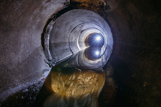 Sewage flowing inside round underground urban sewer tunnel