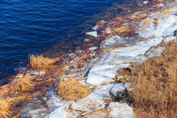 Bank of a wide river with pieces of ice during an ice drift