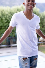Image of african american man in white short sleeve t shirt with copyspace over trees in background