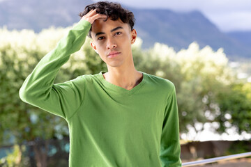 Image of biracial man in green long sleeve top with copyspace over trees in background - Powered by Adobe
