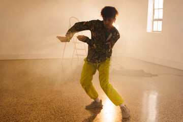 Image of biracial male modern dancer dancing in smoked interior