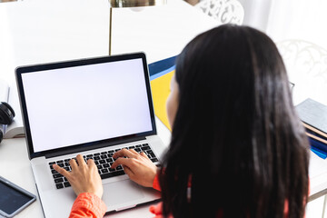 Image of biracial woman using laptop with copy space on screen sitting at desk