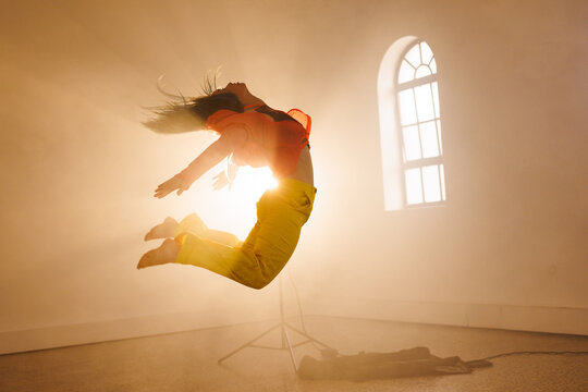 Image of biracial female modern dancer dancing in smoked interior