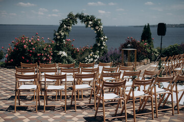 Fototapeta na wymiar wedding ceremony arch with empty chairs and flowers. beautiful romantic decoration