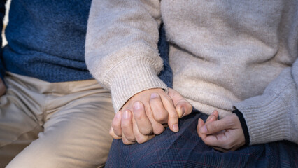 ベンチに座り手を繋ぐ男女