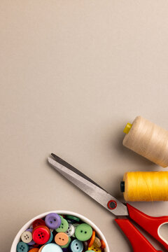 Image of close up of scissors, buttons and threads and copy space on cream background