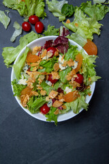 Salad on white plate, on black stone table. Space for text