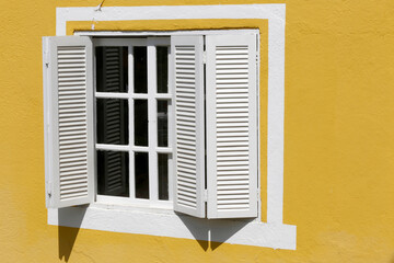 detail of facade of house with white window on yellow wall