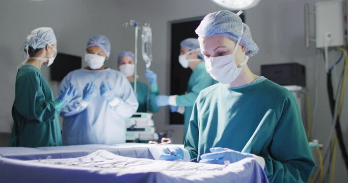 Video of smiling caucasian female surgeon checking instruments in operating theatre, copy space