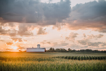 sunset sunrise over a barn in a field