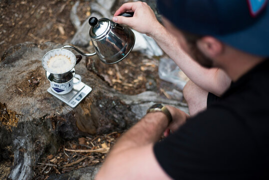High angle view of man pouring coffee in filter at campsite