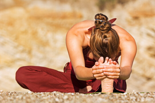 A woman practicing a sitting yoga pose on a beach at Montana de Oro State Park on the Californian coast. California, USA.
