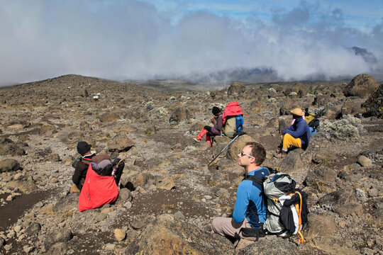 Hiker and local guides resting, along Machame Route of Mt. Kilimanjaro.
