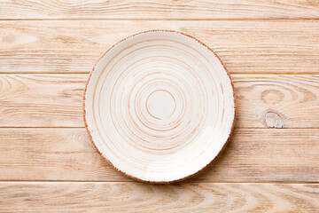 Top view of empty colorful plate on wooden background. Empty space for your design