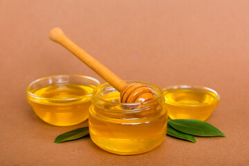 Honey in jar with leaves and honey dipper on colored background top view with copy text