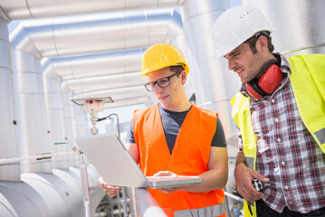 Engineer and worker in meeting with laptop at geothermal power station, Bavaria, Germany