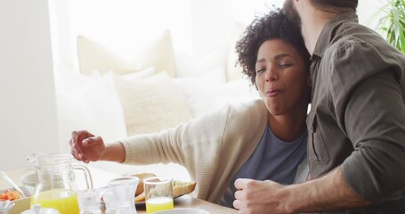 Video of happy diverse couple eating breakfast and talking at table - Powered by Adobe