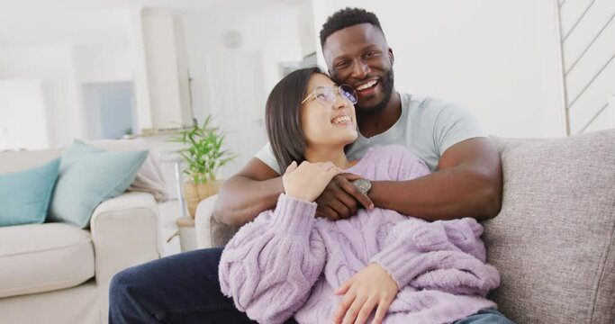 Portrait of happy diverse couple embracing in living room