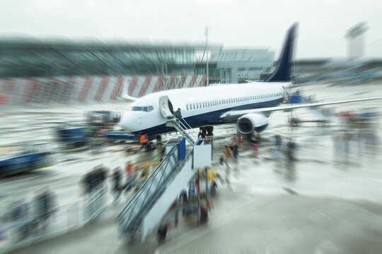 Passengers and workers at unidentified airplane. Blurred zoom image.