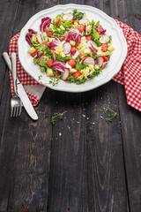 Fresh salad with mixed greens radish cheese and tomato in a plate on wooden background. Italian Mediterranean or Greek cuisine. Vegetarian vegan food.